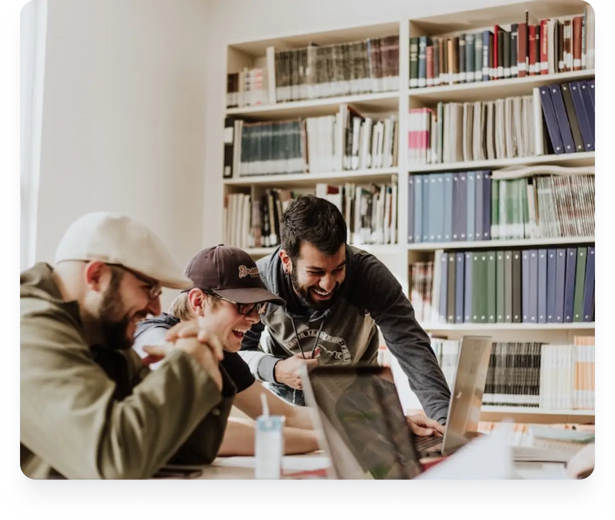 In an office, three men work on laptops, expressing joy over the ease of their membership management software.